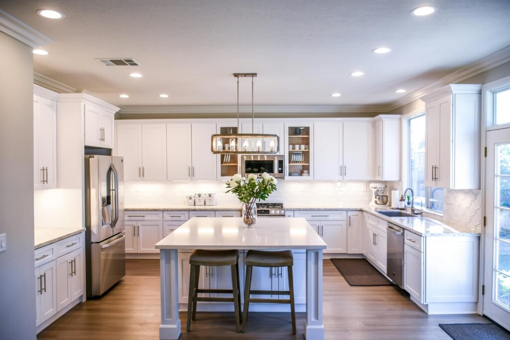 best-kitchen-designs White shaker-style kitchen with a central island, stainless steel appliances, and wood flooring - showcasing a clean, modern kitchen design with natural light and functional layout.