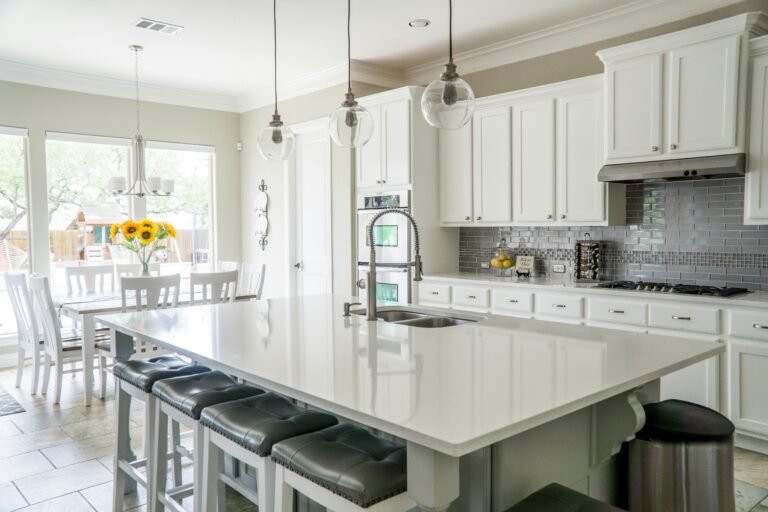 Top 5 Kitchen Design Tips to Maximize Space and Style 3 Bright kitchen interior with gray backsplash tile, pendant lighting, and a large island with bar seating - blending functional space planning with stylish interior design elements.
