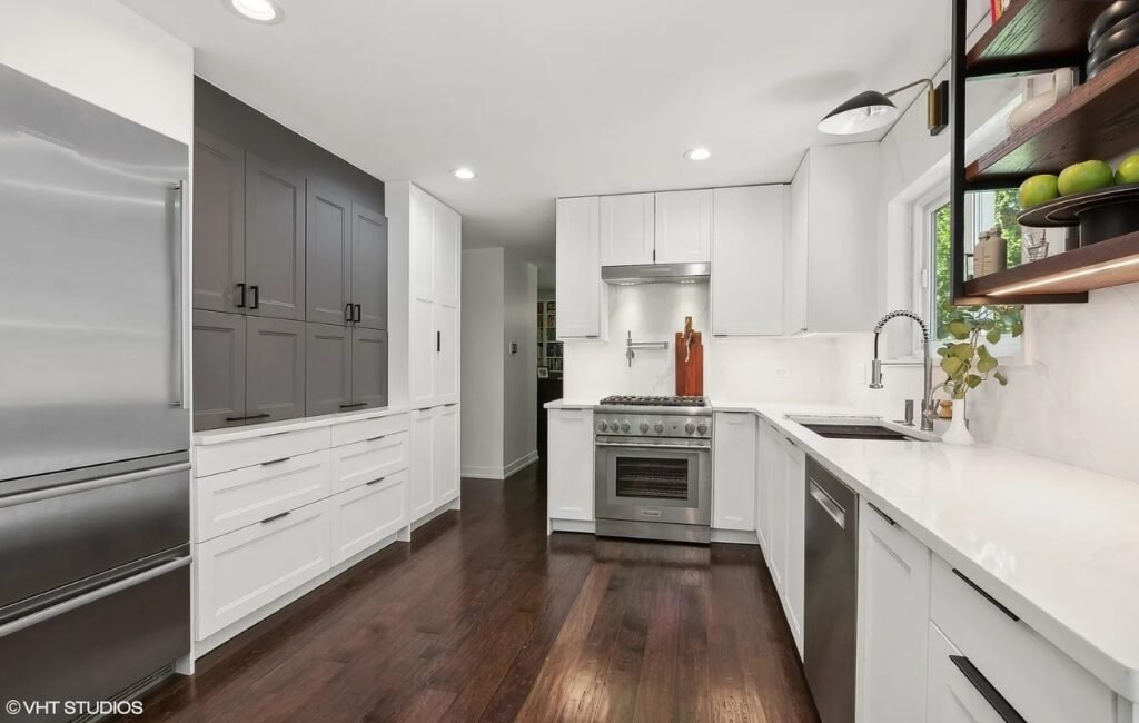 flossmoor-il-kitchen-remodel Wide-angle photo of a modern kitchen remodel in Flossmoor, IL featuring white cabinets, dark hardwood floors, and stainless steel appliances.